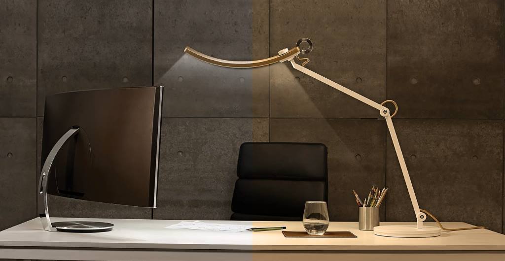 Person adjusting desk lamps for even face lighting during video call in dim room.